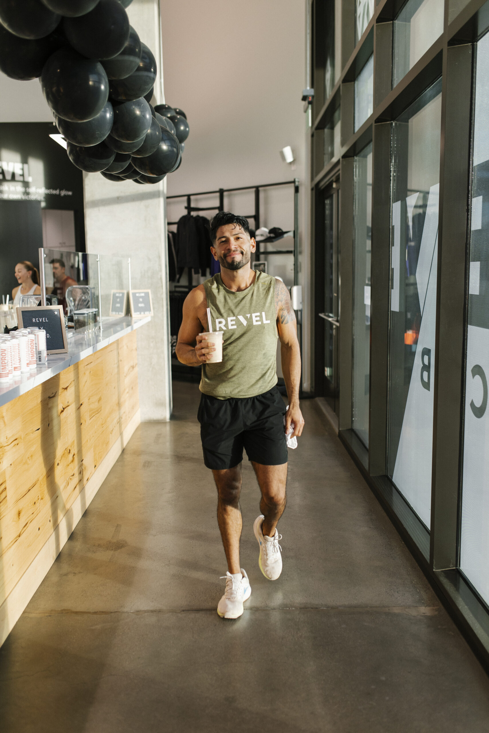 Member walking through the REVEL Fit Club lobby with a smoothie